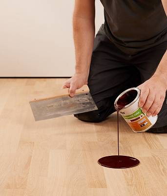 Handwerker trägt Parkettöl auf Holzboden auf und verteilt die Pflege sorgfältig zur Veredelung der Oberfläche.