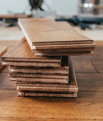 Gestapelte Holzdielen aus Eiche in einer Werkstatt, Detailansicht der Nut- und Federprofile mit sichtbarer Holzstruktur.