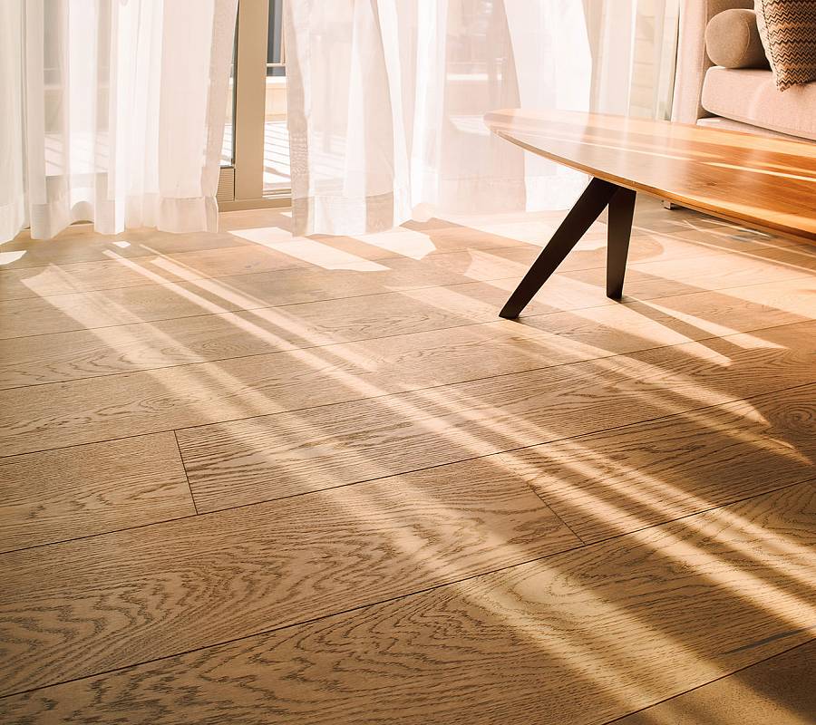 Wohnraum mit natürlicher Landhausdiele aus Eiche, warmem Sonnenlicht, modernem Couchtisch und ruhiger Wohnatmosphäre.