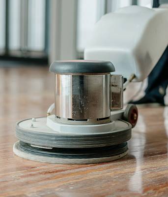 Poliermaschine bei der Oberflächenbehandlung eines Holzbodens, glänzendes Finish und gleichmäßige Bearbeitung.