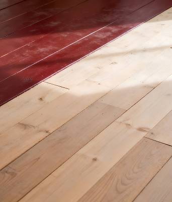 Holzdielenboden mit teils roter Ochsenblut-Beschichtung und teils abgeschliffener, heller Naturholzfläche.