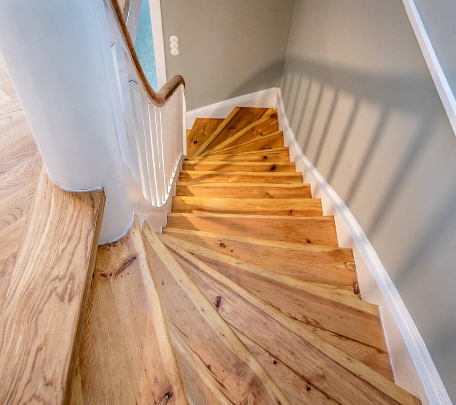 Holztreppe mit massiven Stufen in warmem Naturton und weißem Geländer