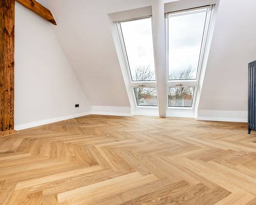 Dachgeschoss mit hellem Fischgrätparkett und großen Dachfenstern