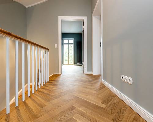 Flur mit Eichen-Fischgrätparkett und weißem Treppengeländer