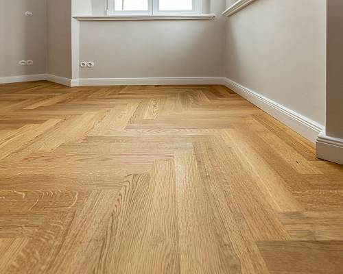 Nahaufnahme von hellem Fischgrätparkett mit sauberer Sockelleiste