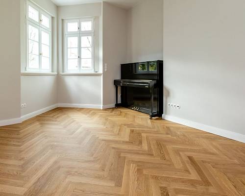 Helles Fischgrätparkett im Altbau mit Klavier und großen Fenstern