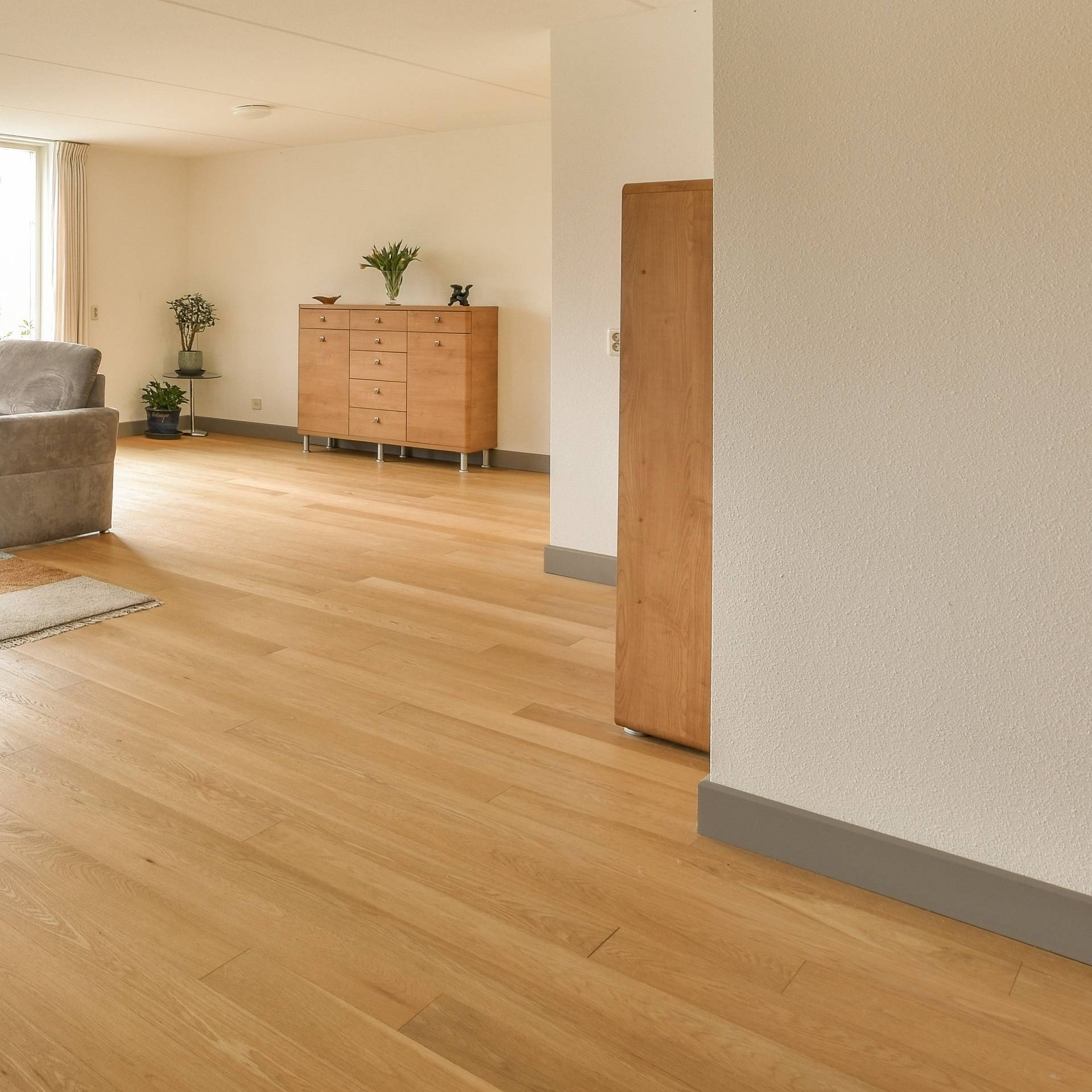 Wohnraum mit geschliffenem Eichenparkett und schlichter Einrichtung