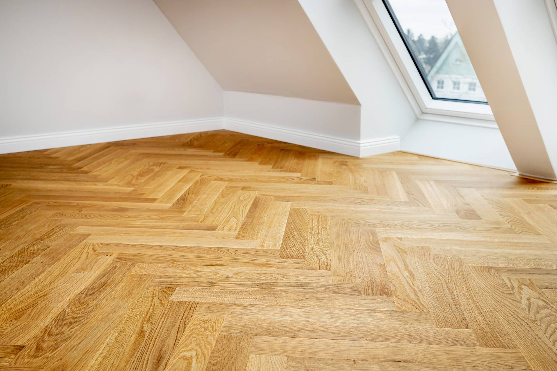 Helles Stäbchenparkett aus Eiche in einem Dachraum mit schrägen Wänden, viel Tageslicht und klarer, moderner Optik.