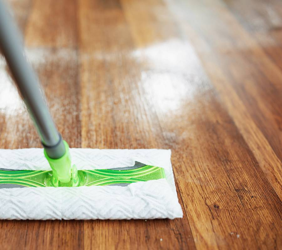 Parkettboden wird feucht gewischt mit Mopp und Reinigungsmittel