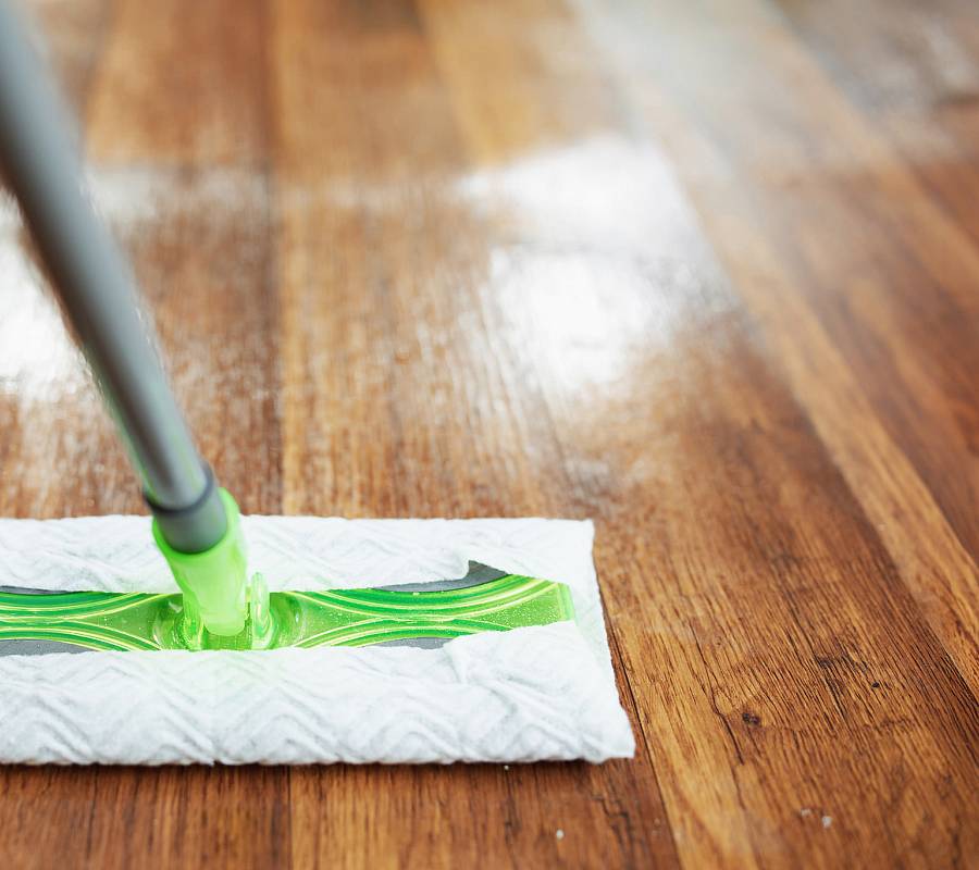 Parkettboden wird feucht gewischt mit Mopp und Reinigungsmittel