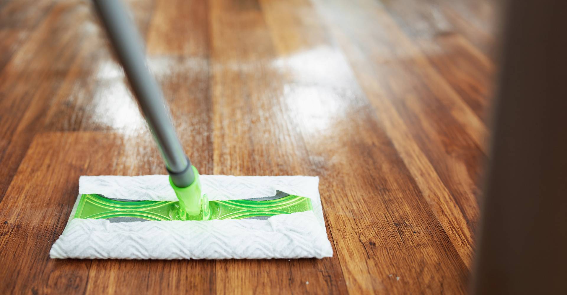 Parkettboden wird feucht gewischt mit Mopp und Reinigungsmittel