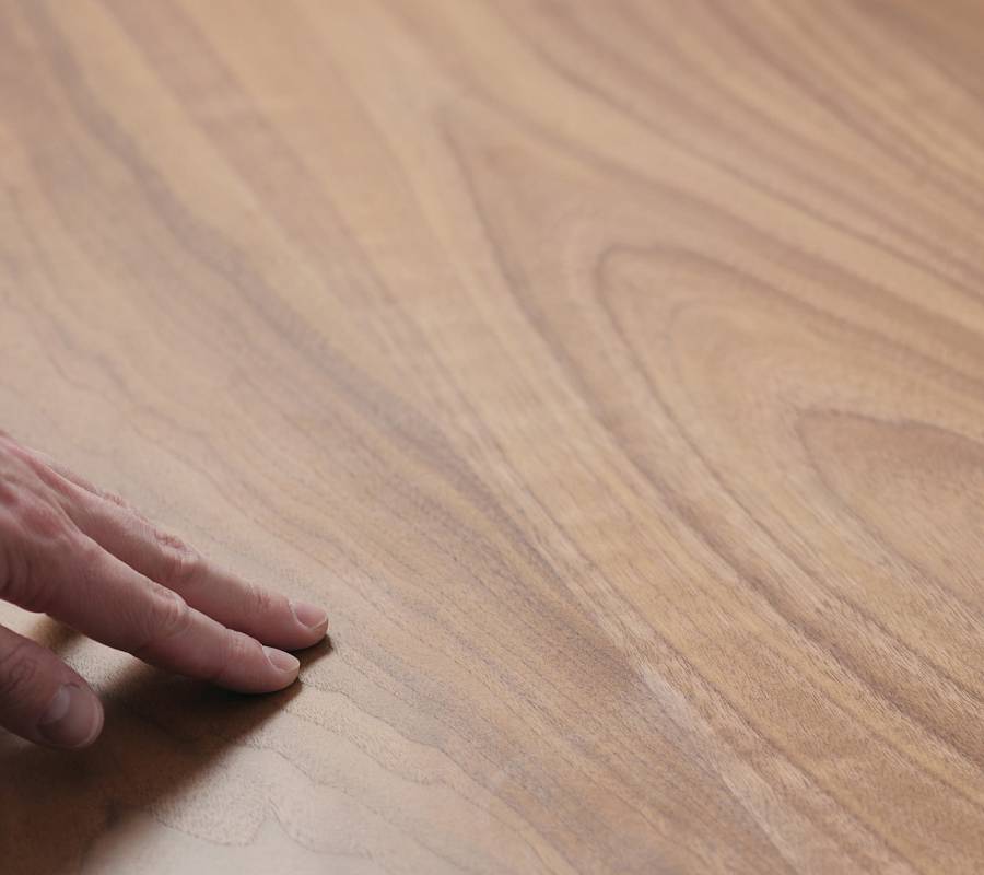 Hand prüft glatte Oberfläche eines geölten Holzbodens mit sichtbarer Maserung