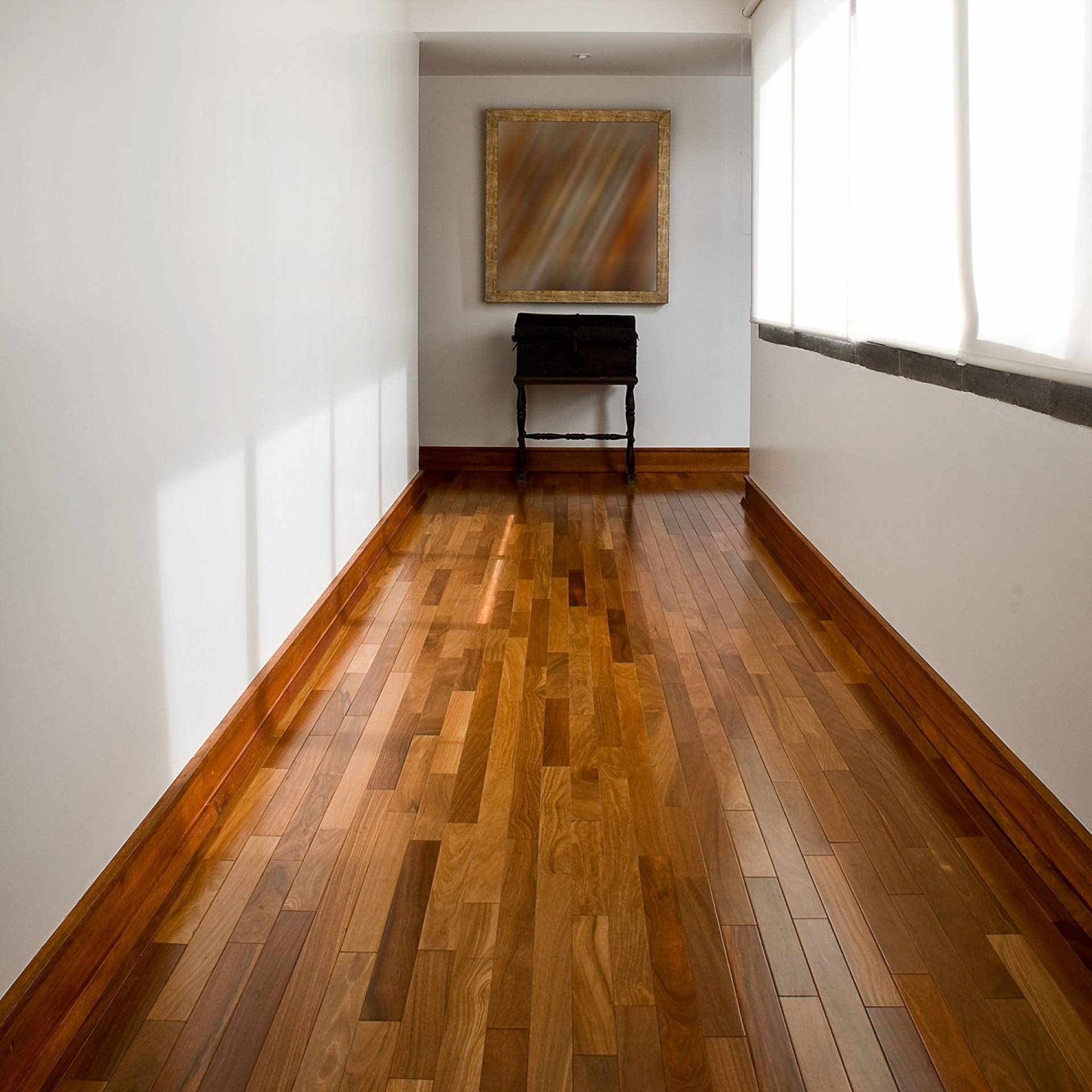 Schmaler Flur mit glänzendem Stabparkett und warmem Holzton