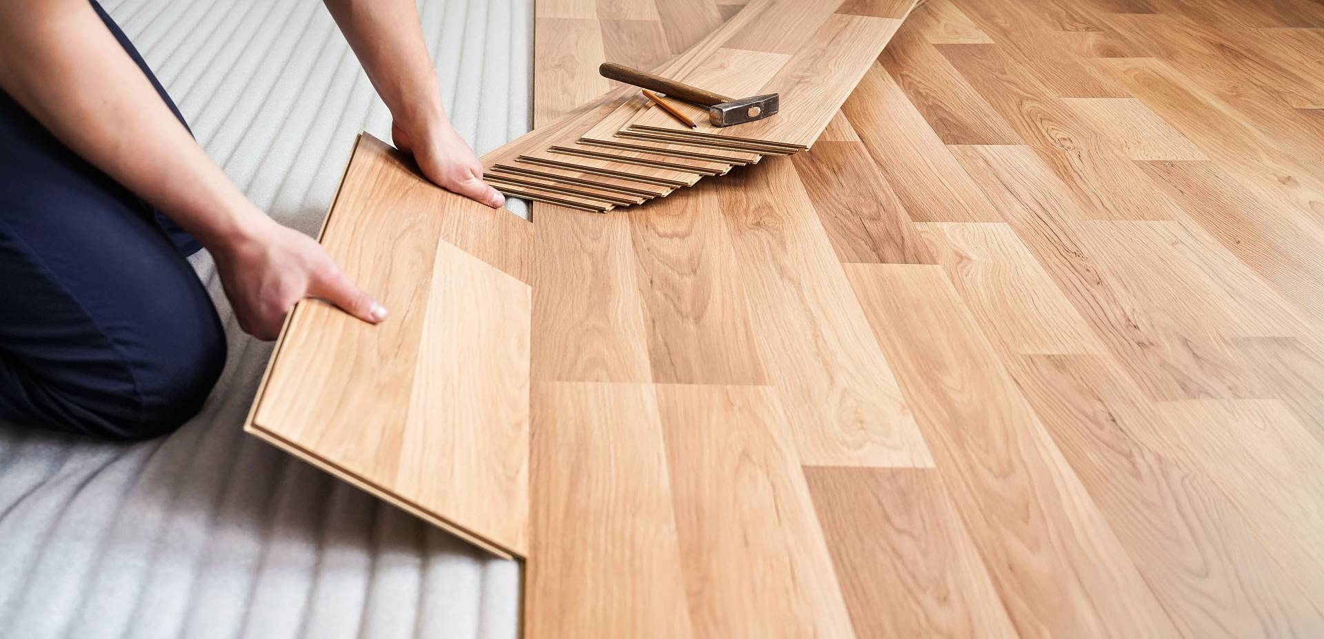 Handwerker verlegt Laminatboden fachgerecht in Wohnraum auf Trittschalldämmung.