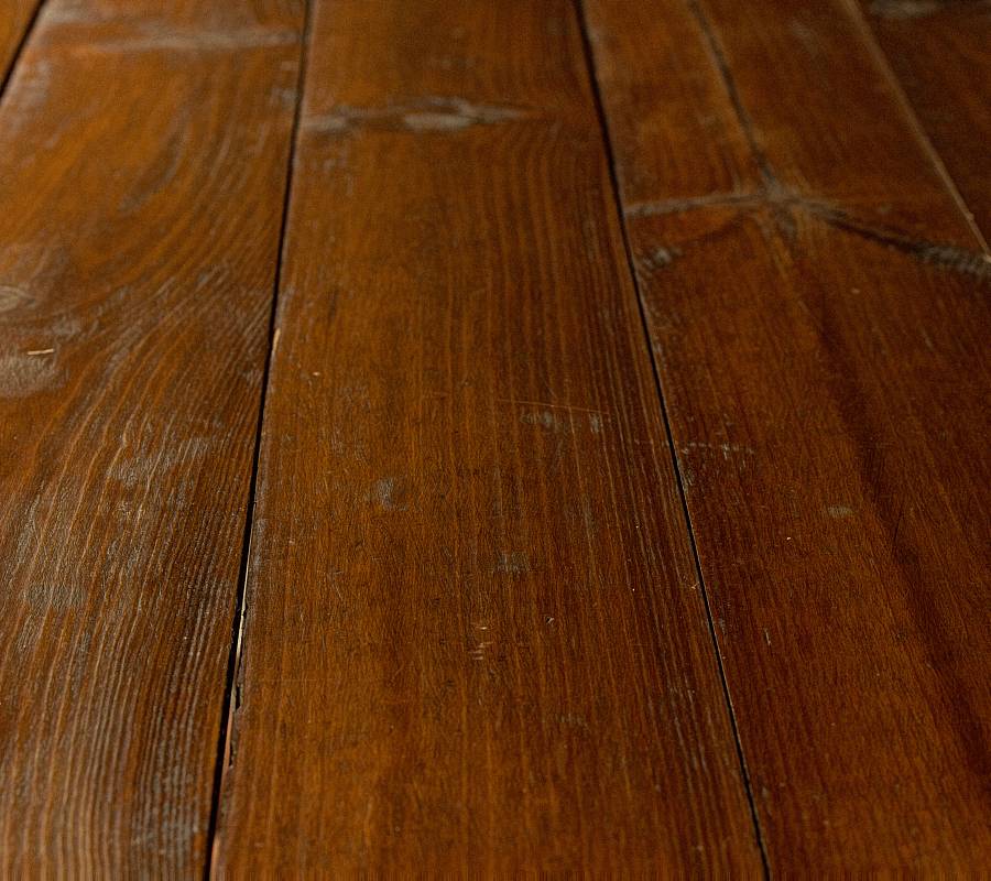 Dunkle Holzdielen mit sichtbaren Gebrauchsspuren und natürlicher Struktur