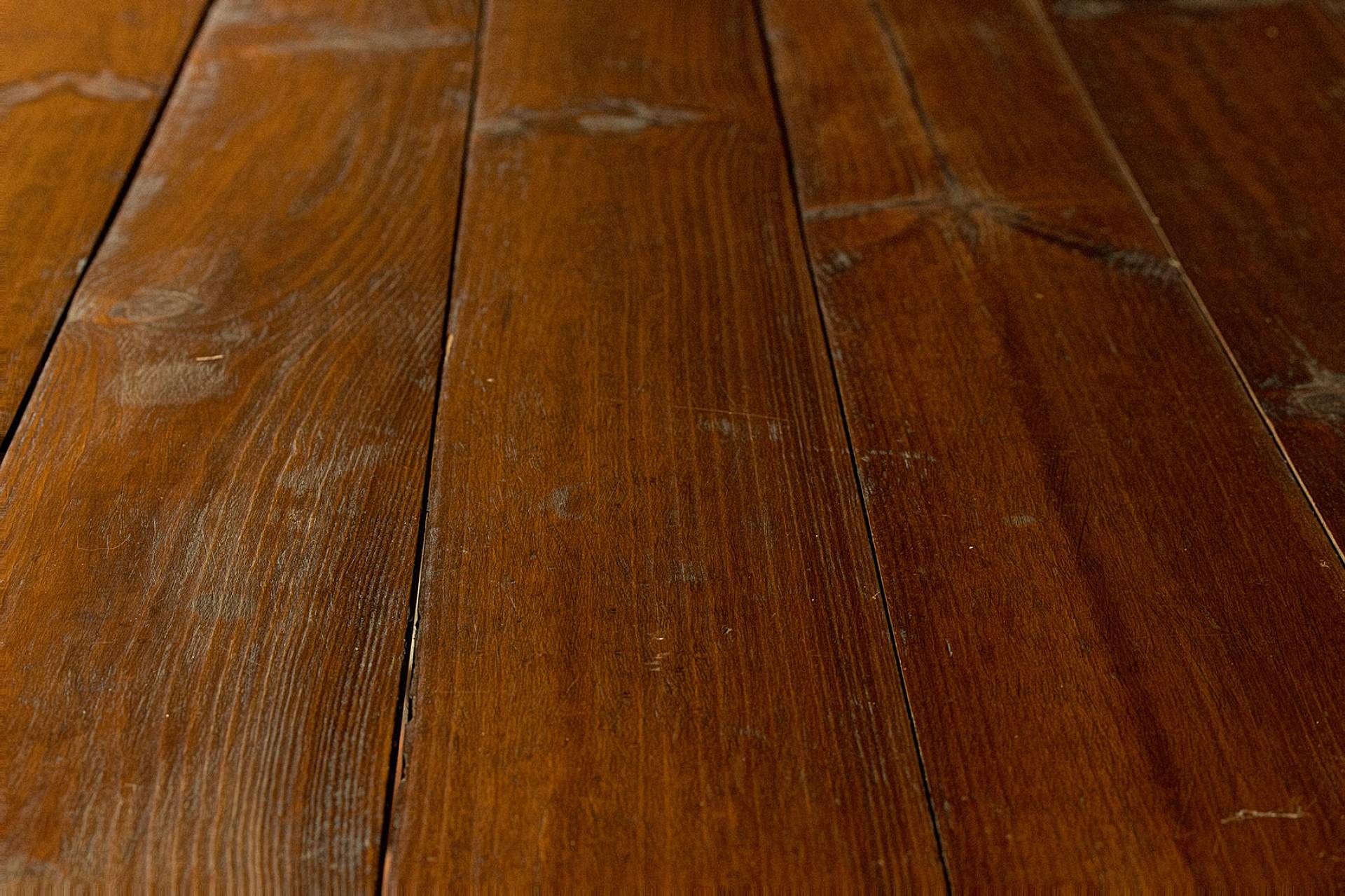 Dunkle Holzdielen mit sichtbaren Gebrauchsspuren und natürlicher Struktur