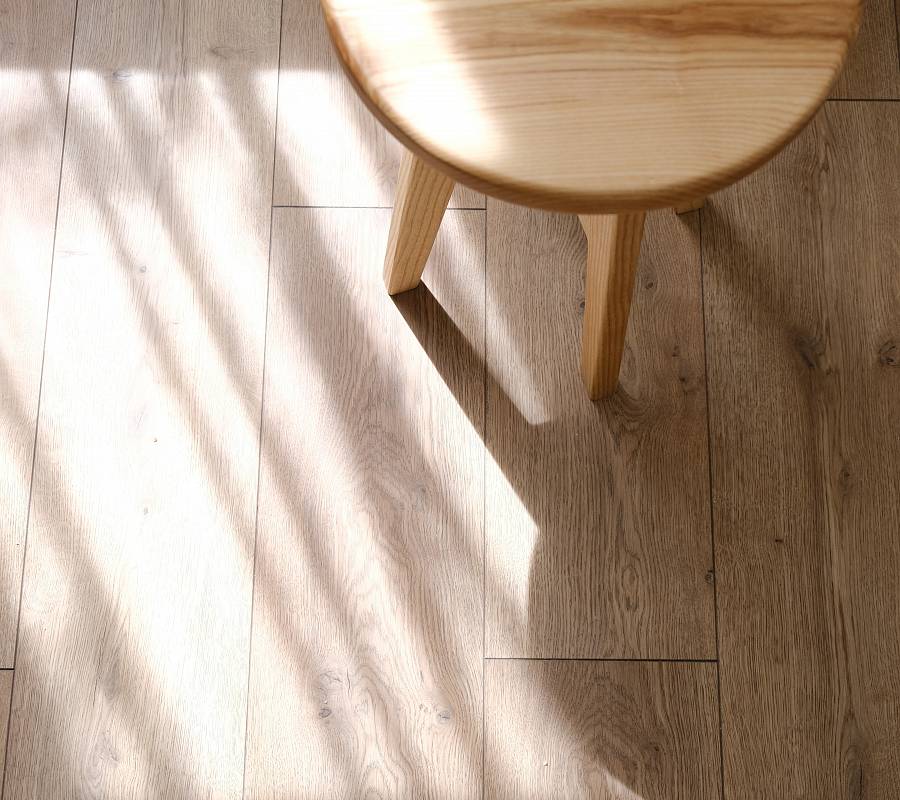 Heller Parkettboden mit Stuhl und weichem Licht-Schatten-Spiel