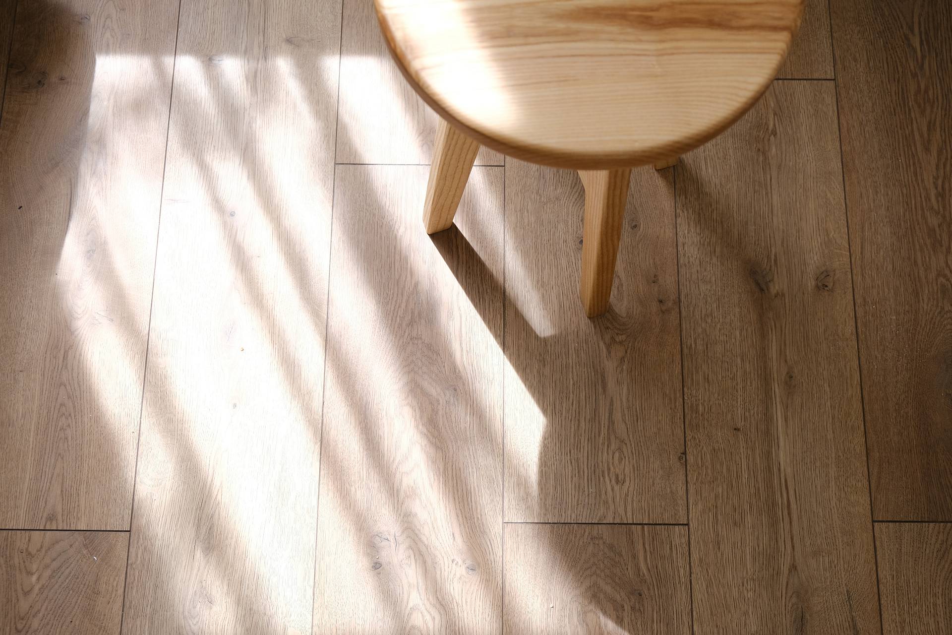 Heller Parkettboden mit Stuhl und weichem Licht-Schatten-Spiel