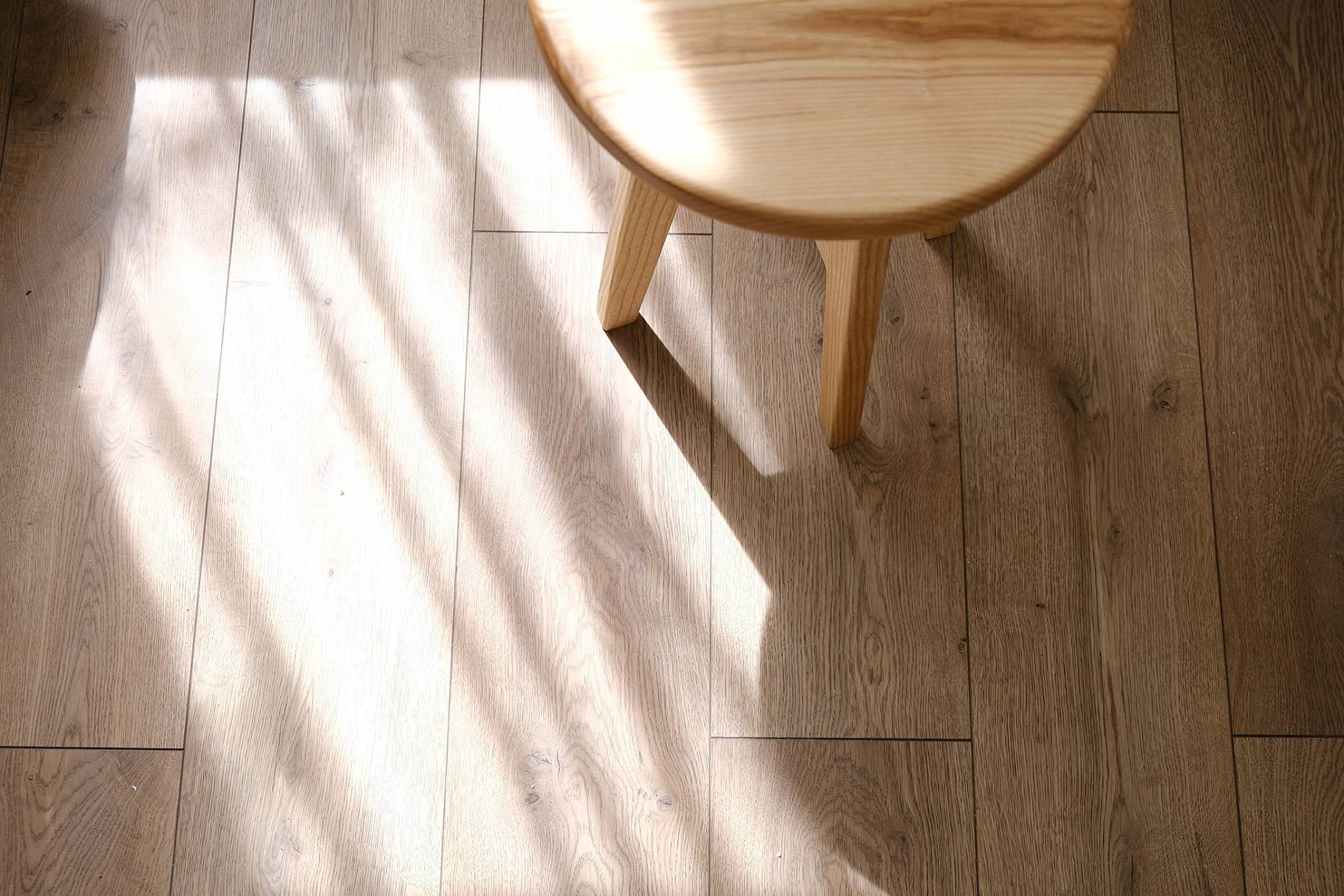 Heller Parkettboden mit Stuhl und weichem Licht-Schatten-Spiel