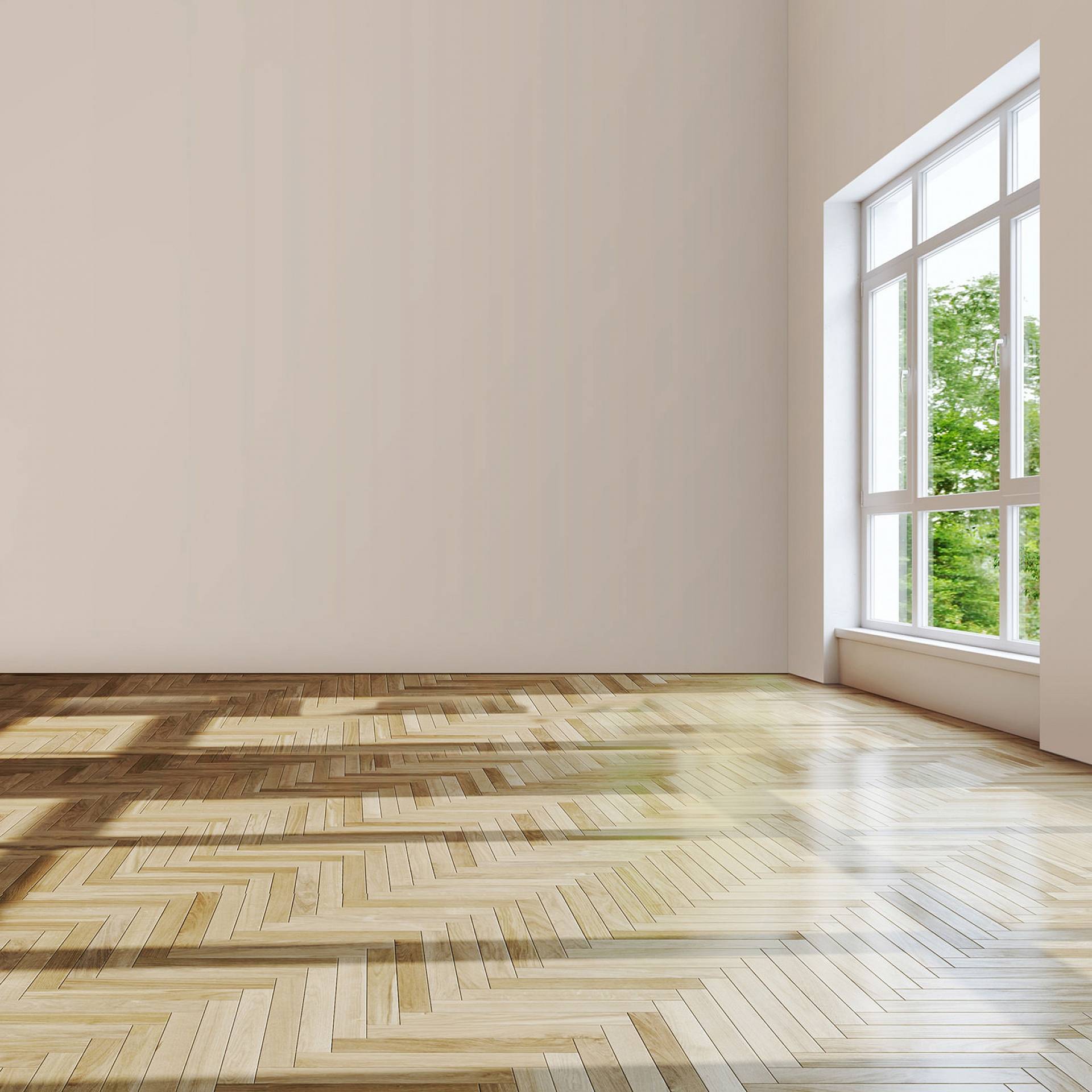 Leerer Raum mit hellem Fischgrätparkett und großer Fensterfront