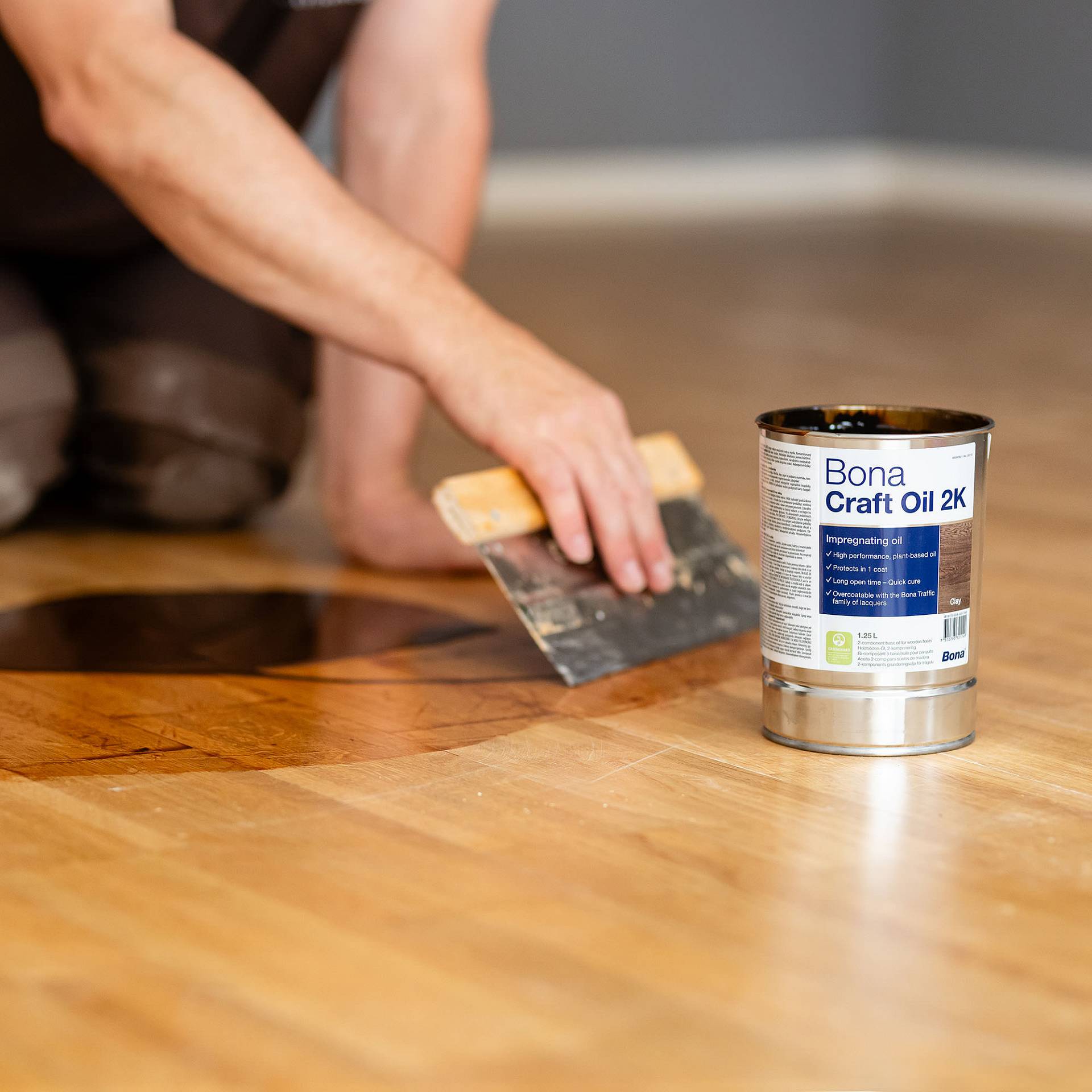 Parkett wird mit Spachtel versiegelt, Lackdose steht daneben