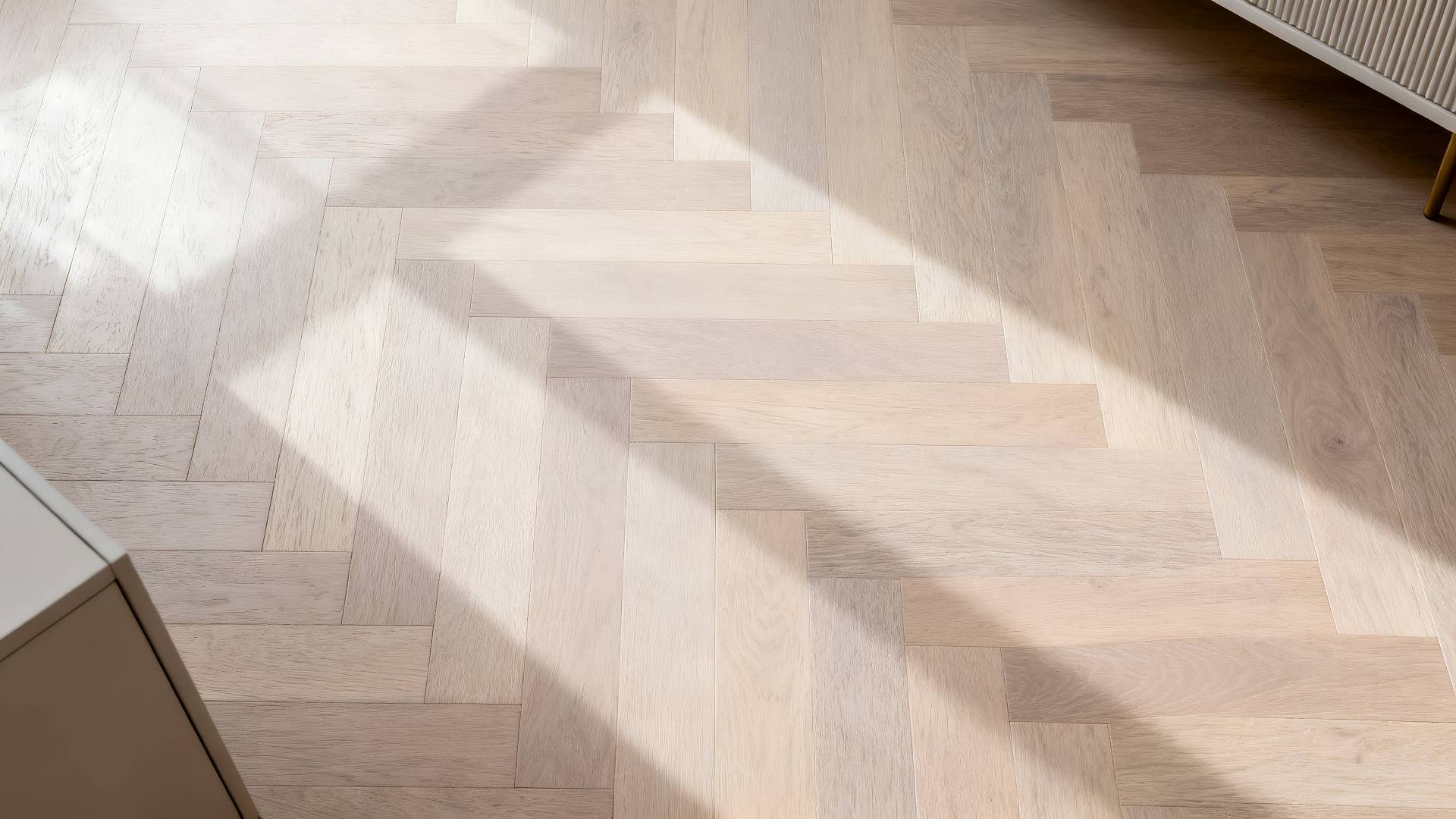 Heller Raum mit modernem Fischgrätparkett, auf den Sonnenlicht durch große Fenster fällt.