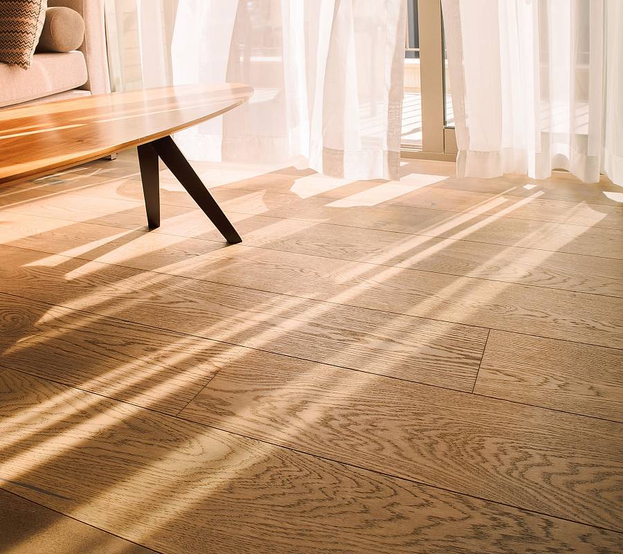 Heller Parkettboden im Wohnzimmer mit weichem Sonnenlicht und Schatten