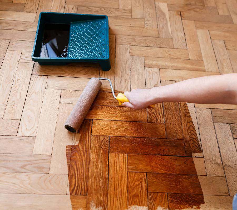 Fischgrätparkett wird mit Farbrolle neu versiegelt im Innenraum