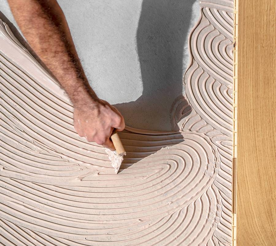 Zahnspachtel verteilt Parkettkleber gleichmäßig auf dem Untergrund