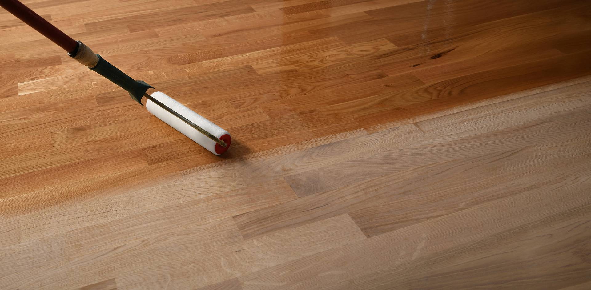 Parkettboden wird mit Rolle geölt, deutlicher Vorher-Nachher-Effekt