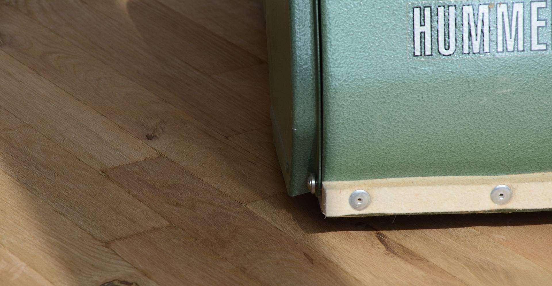 Detailaufnahme einer Hummel Bandschleifmaschine auf einem Holzparkett