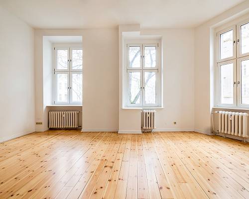 Lichtdurchfluteter Raum mit neu verlegtem Dielenboden und Heizkörpern