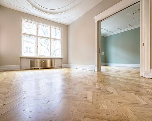 Großzügiger Raum mit neu verlegtem Fischgrätparkett und Stuckdecke