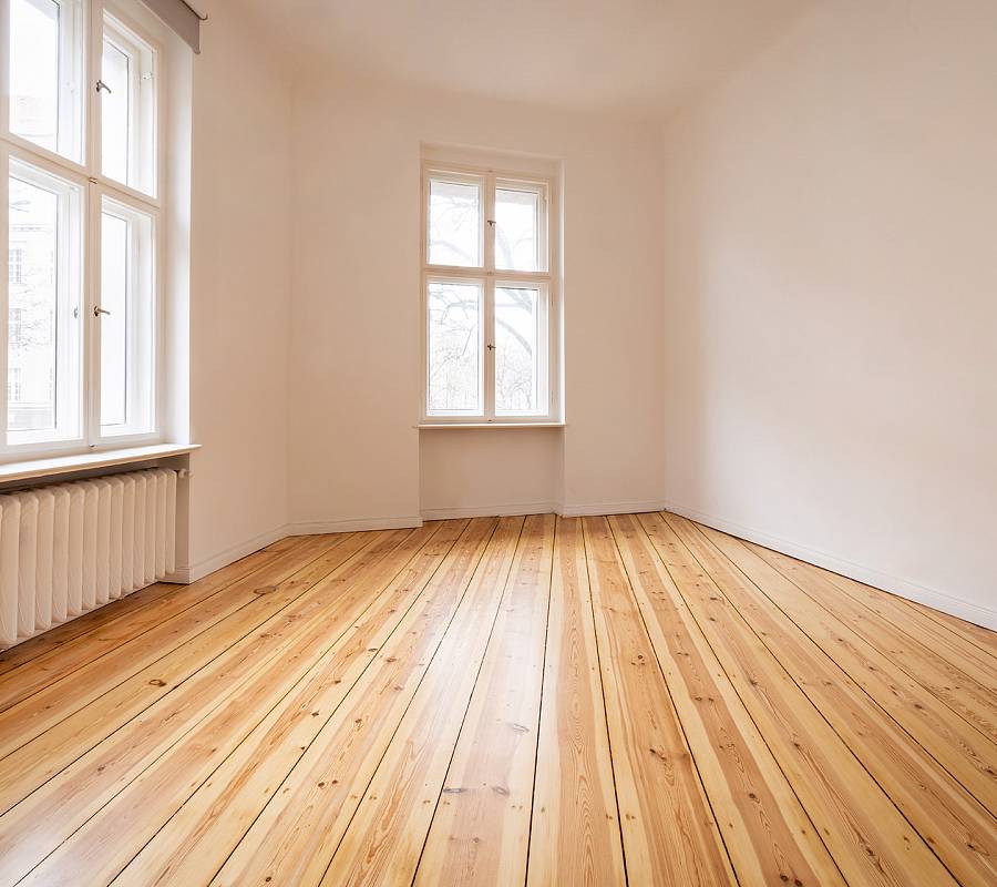 Leerer Raum mit frisch geschliffenen Holzdielen und großen Fenstern