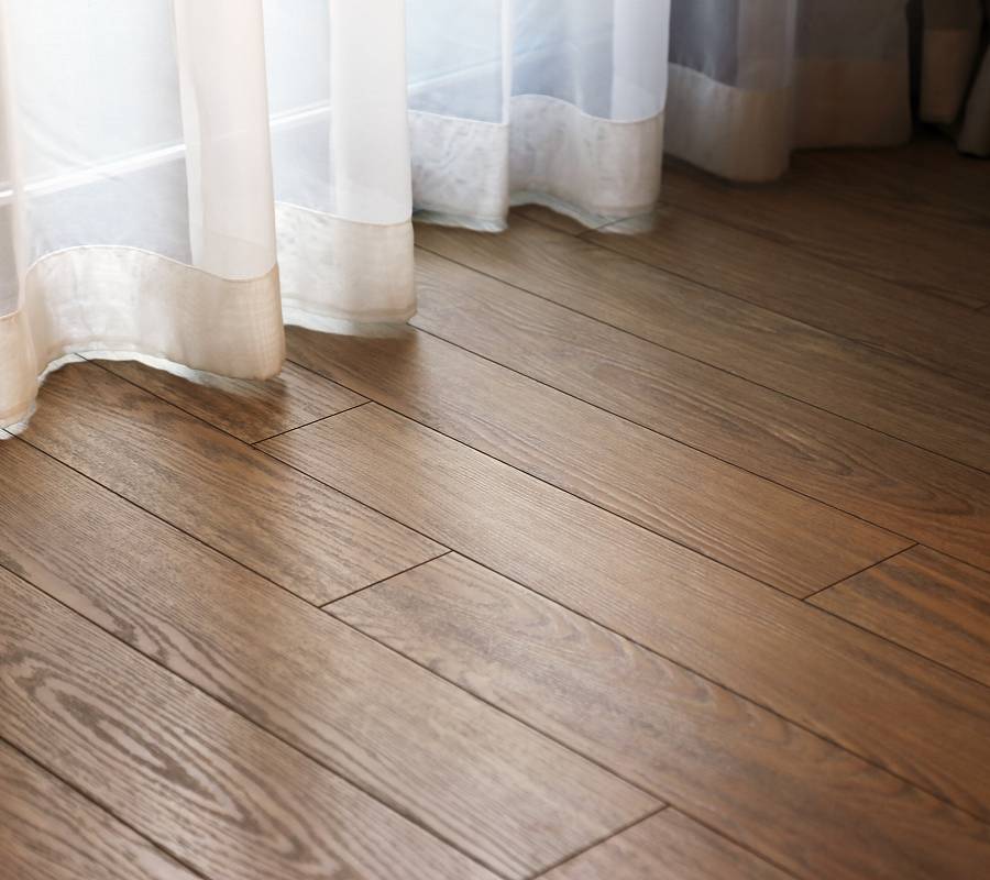 Dunkler Parkettboden mit Vorhang im warmen Tageslicht