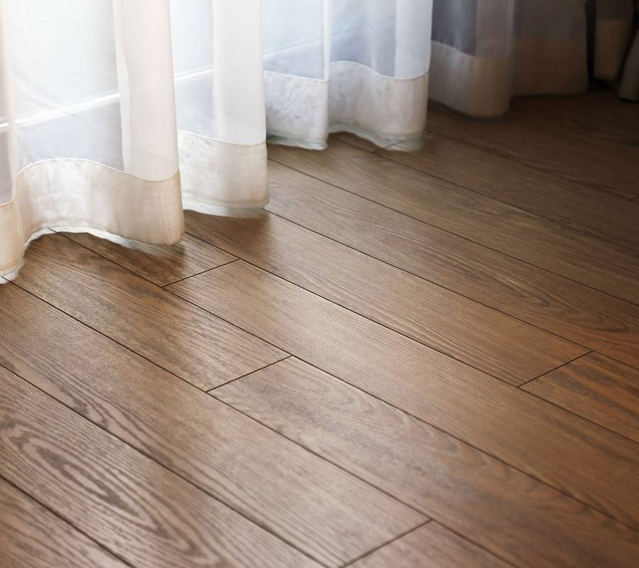 Dunkler Parkettboden mit Vorhang im warmen Tageslicht