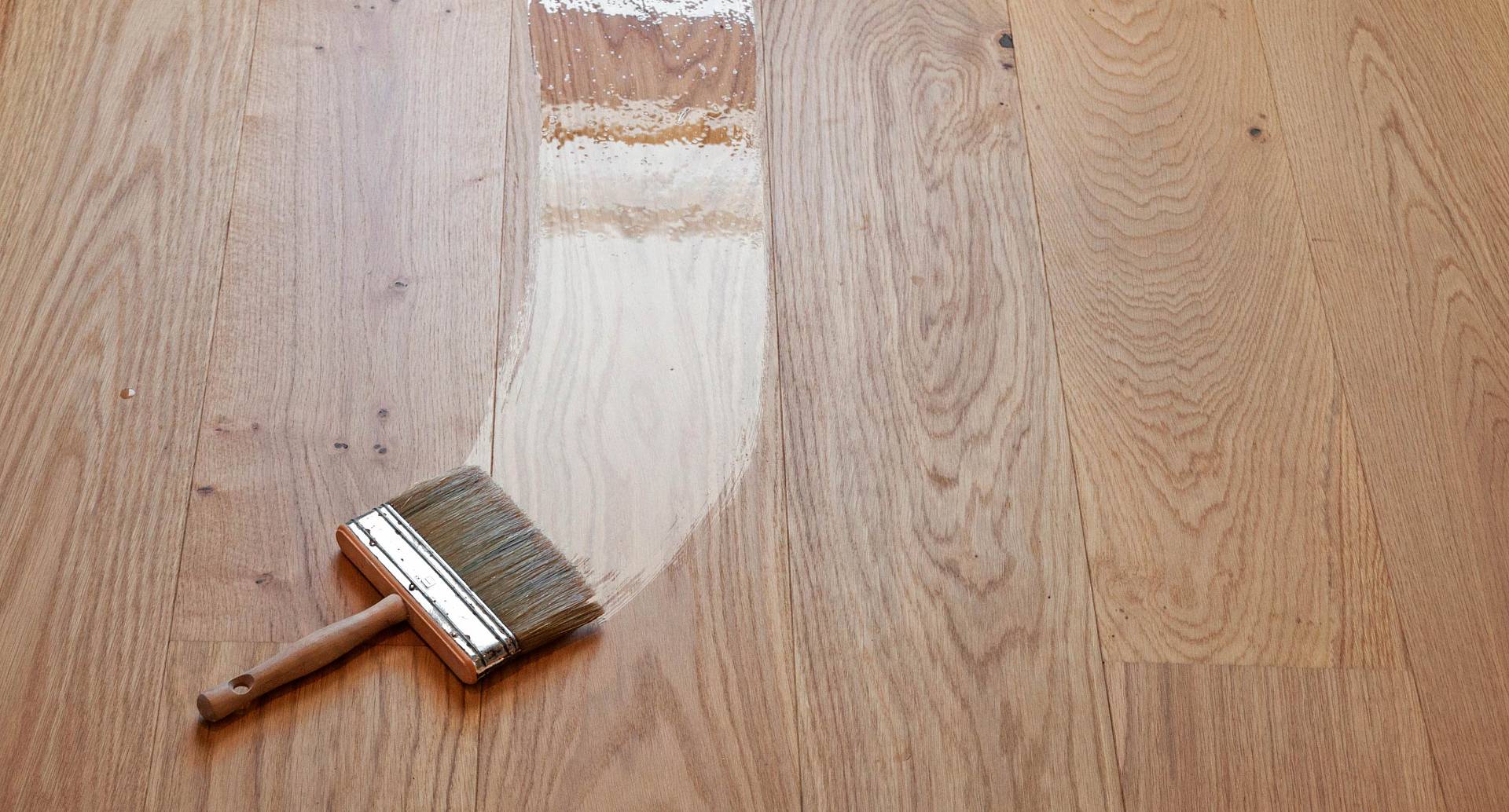 Pinsel trägt Holzöl auf Eichenparkett auf und zeigt Vorher-Nachher-Effekt