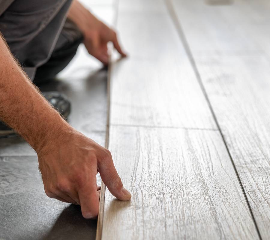 Handwerker verlegt helle Landhausdiele präzise auf vorbereitetem Untergrund