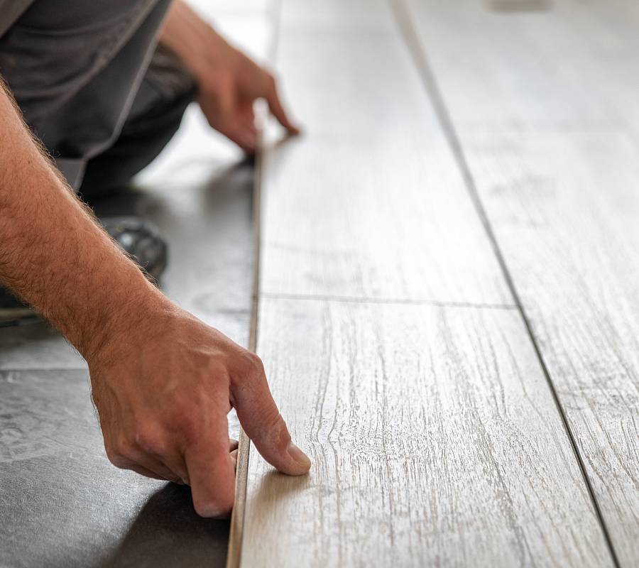 Handwerker verlegt helle Landhausdiele präzise auf vorbereitetem Untergrund