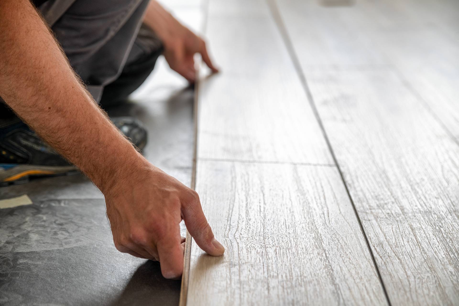 Handwerker verlegt helle Landhausdiele präzise auf vorbereitetem Untergrund