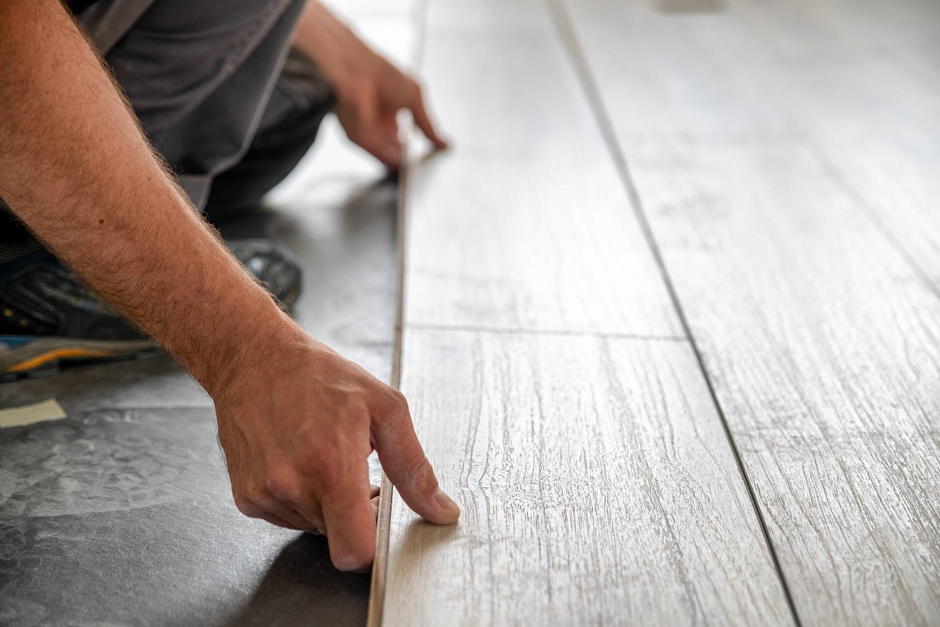 Handwerker verlegt helle Landhausdiele präzise auf vorbereitetem Untergrund