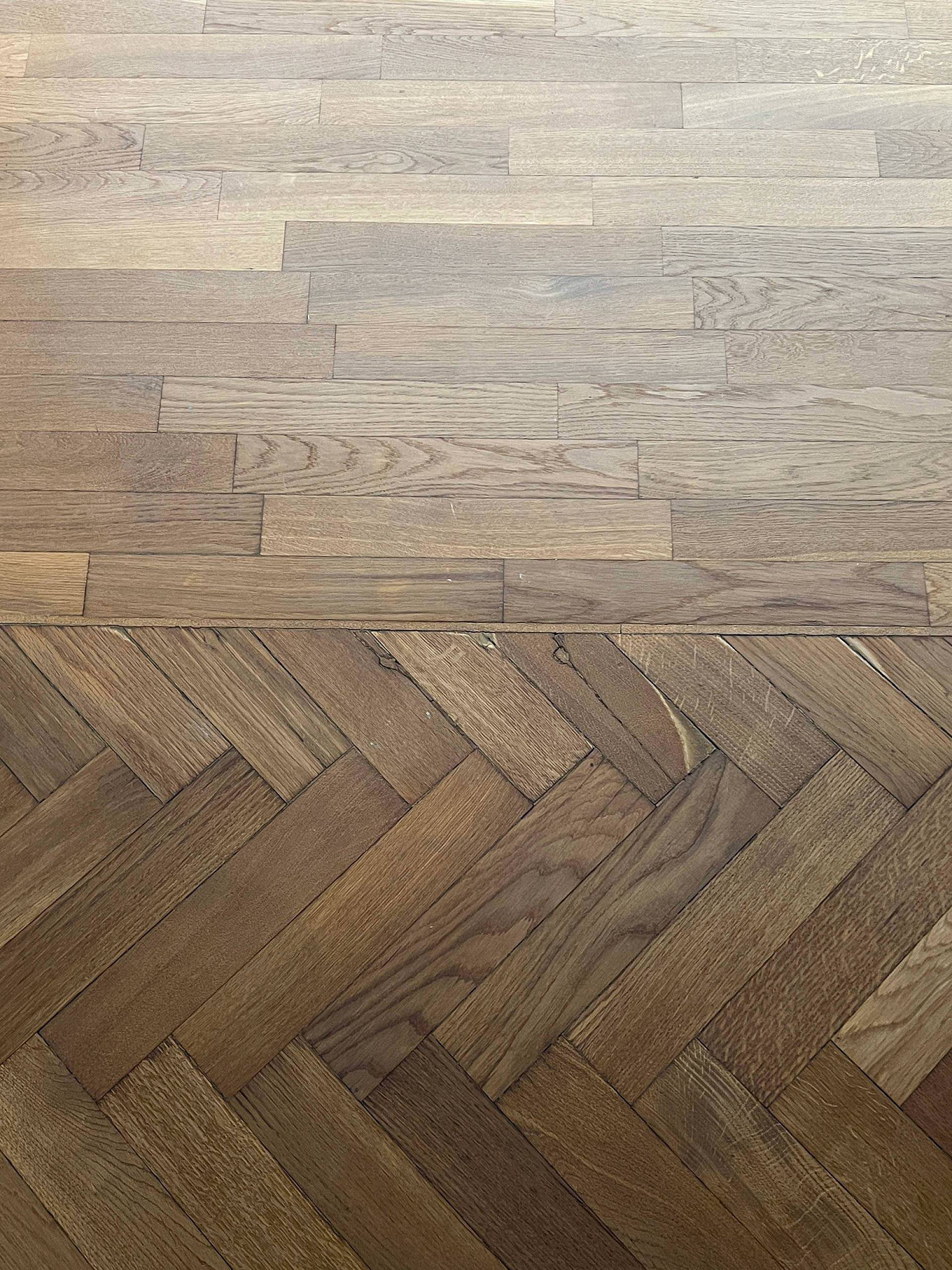 Übergang zwischen hellem Landhausdielenboden und dunklem Fischgrätparkett