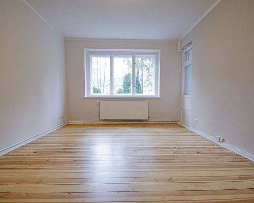 Heller Wohnraum mit frisch abgeschliffenen Kieferndielen und großem Fenster
