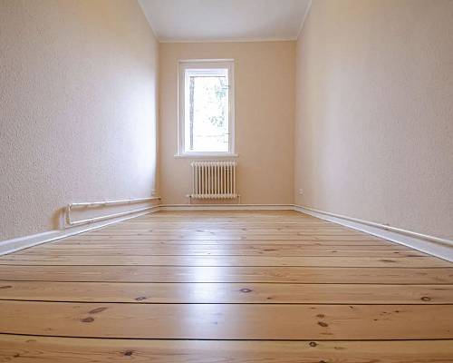 Schmaler Raum mit aufgearbeiteten Holzdielen und klassischem Heizkörper
