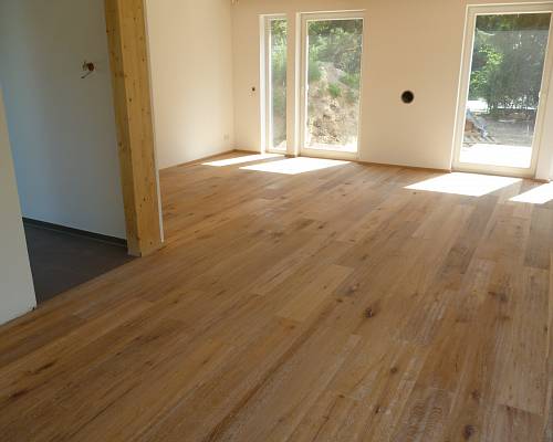 Großzügiger Wohnraum mit naturgeöltem Eichenboden und bodentiefen Fenstern.