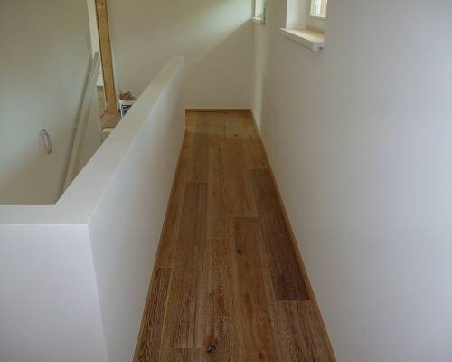 Obergeschoss mit durchgehendem Eichenboden und moderner Treppenbrüstung.