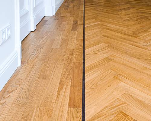 Übergang zwischen Stabparkett und Fischgrät mit dunkler Trennfuge im Altbau.