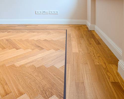 Fischgrätparkett mit umlaufendem Fries und klarer Linienführung im Wohnraum.
