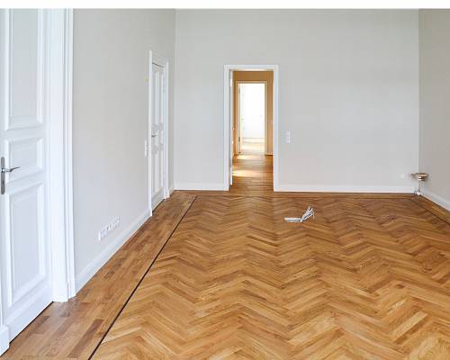 Altbauzimmer mit aufgearbeitetem Fischgrätparkett und klassischer Türanlage.