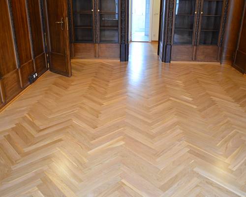 Symmetrischer Blick über frisch geschliffenes Fischgrätparkett im Altbaubüro.